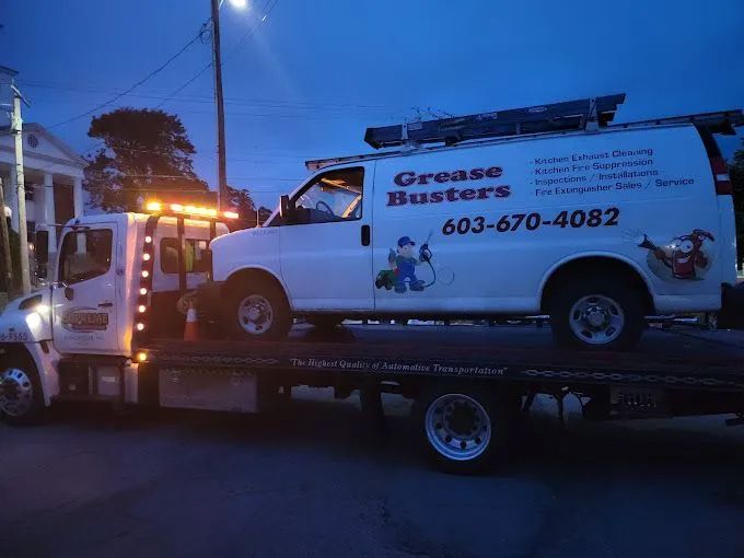 A grease busters van is being towed by a tow truck
