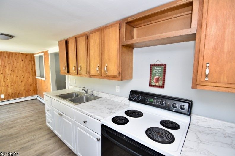 A kitchen with a stove , sink , and cabinets.