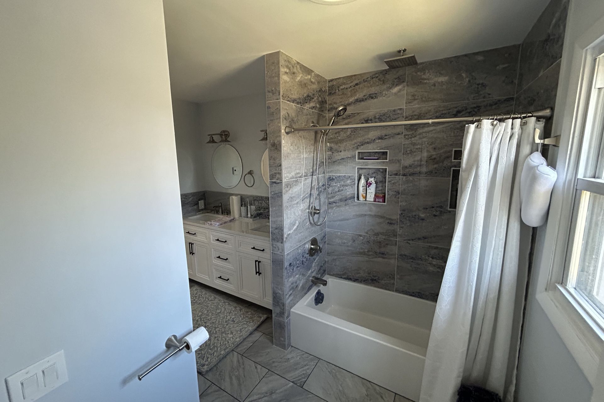 A bathroom with a tub , shower , sink and mirror.