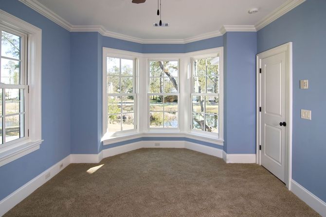An empty room with blue walls and a bay window.