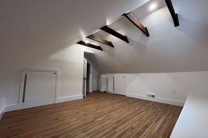 An empty attic with wooden floors and white walls