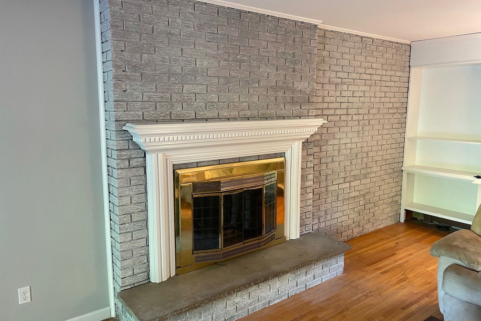 A living room with a fireplace and a brick wall.