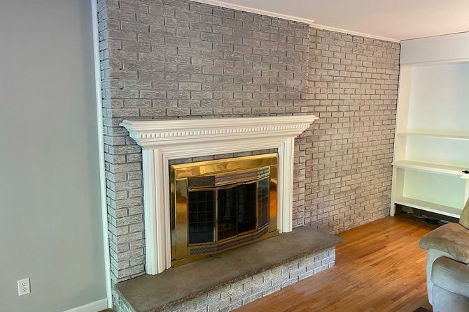 A living room with a fireplace and a brick wall.