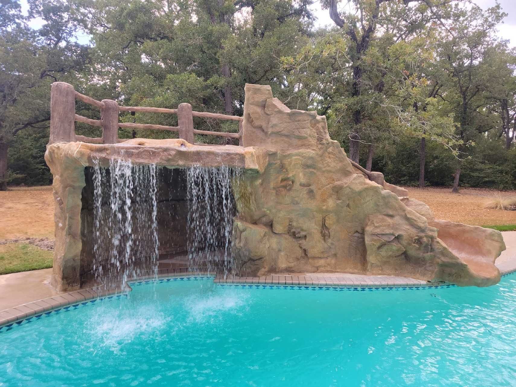 There is a waterfall in the middle of a swimming pool.