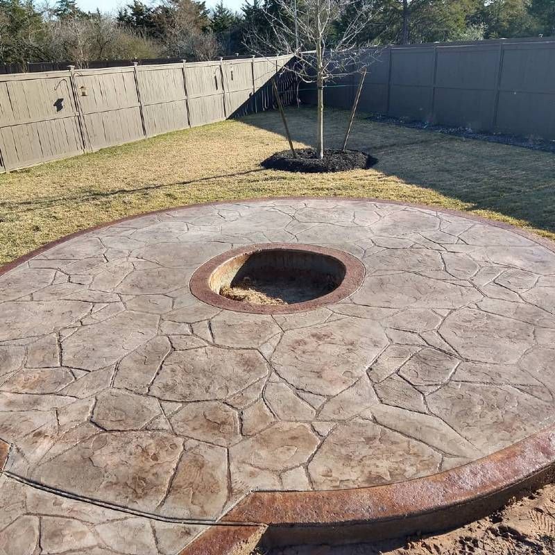 A concrete patio with a fire pit in the middle