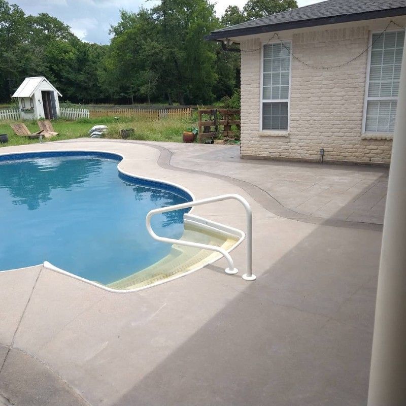A large swimming pool is surrounded by a brick house