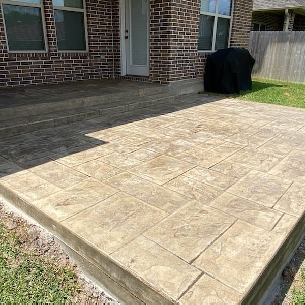 A brick house with a concrete patio in front of it.