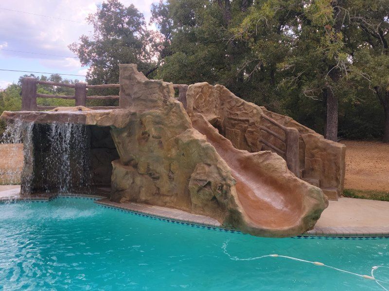 A swimming pool with a waterfall and a slide