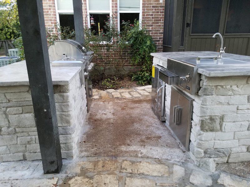 A kitchen with a sink and a grill in front of a brick house.