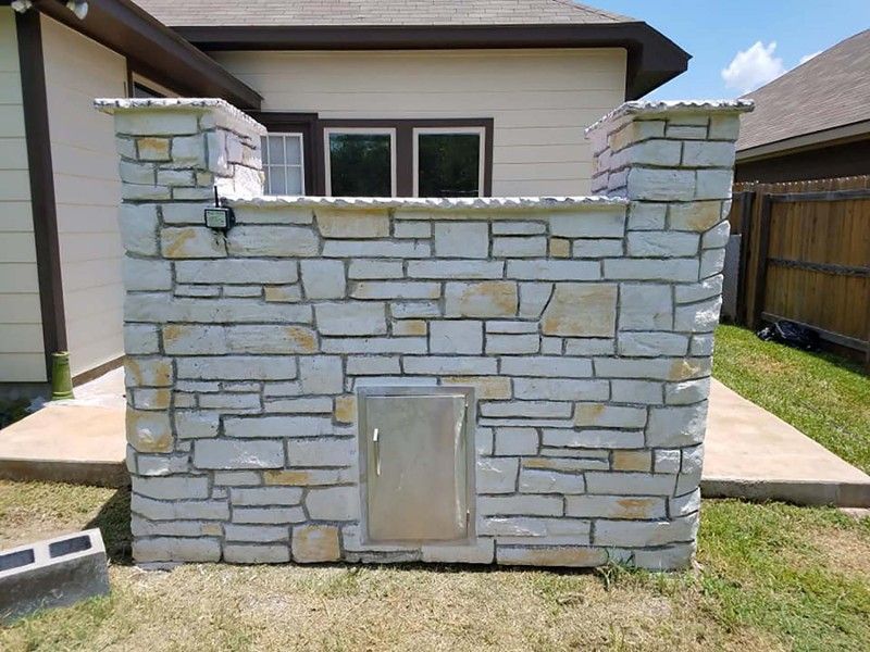 A stone wall with a stainless steel door in front of a house.