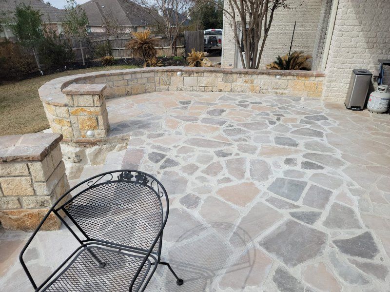 A chair is sitting on a stone patio next to a stone wall.