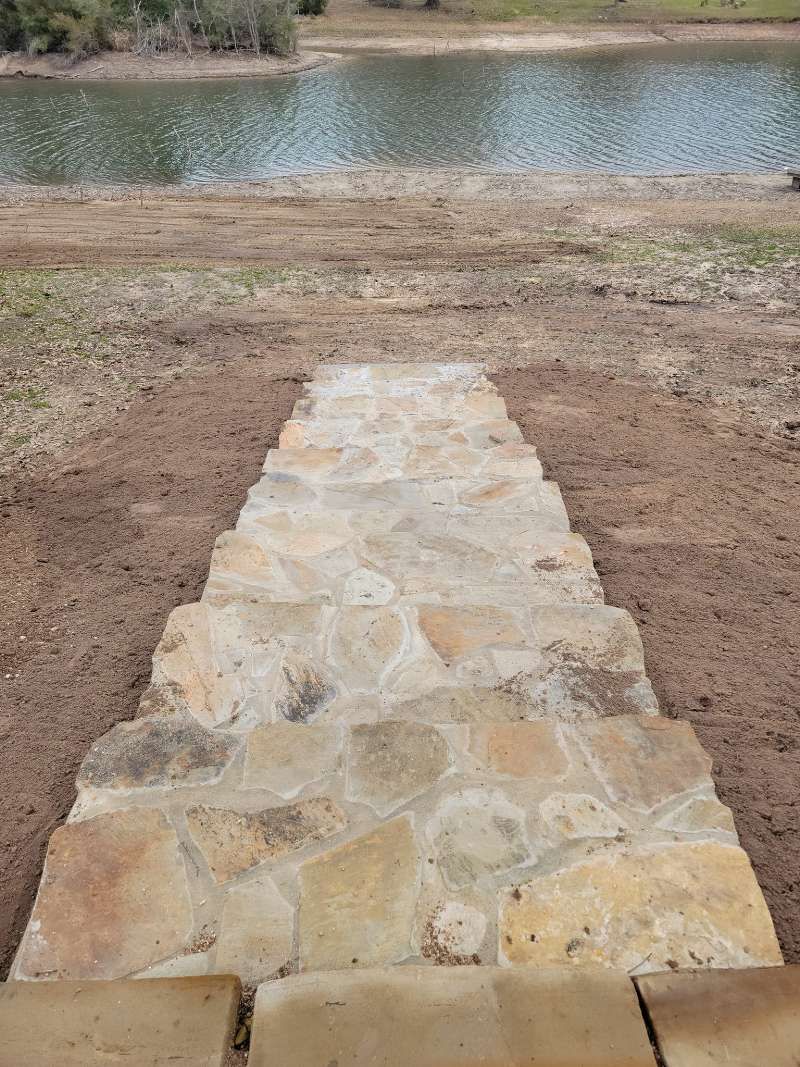 A stone walkway leading to a body of water.