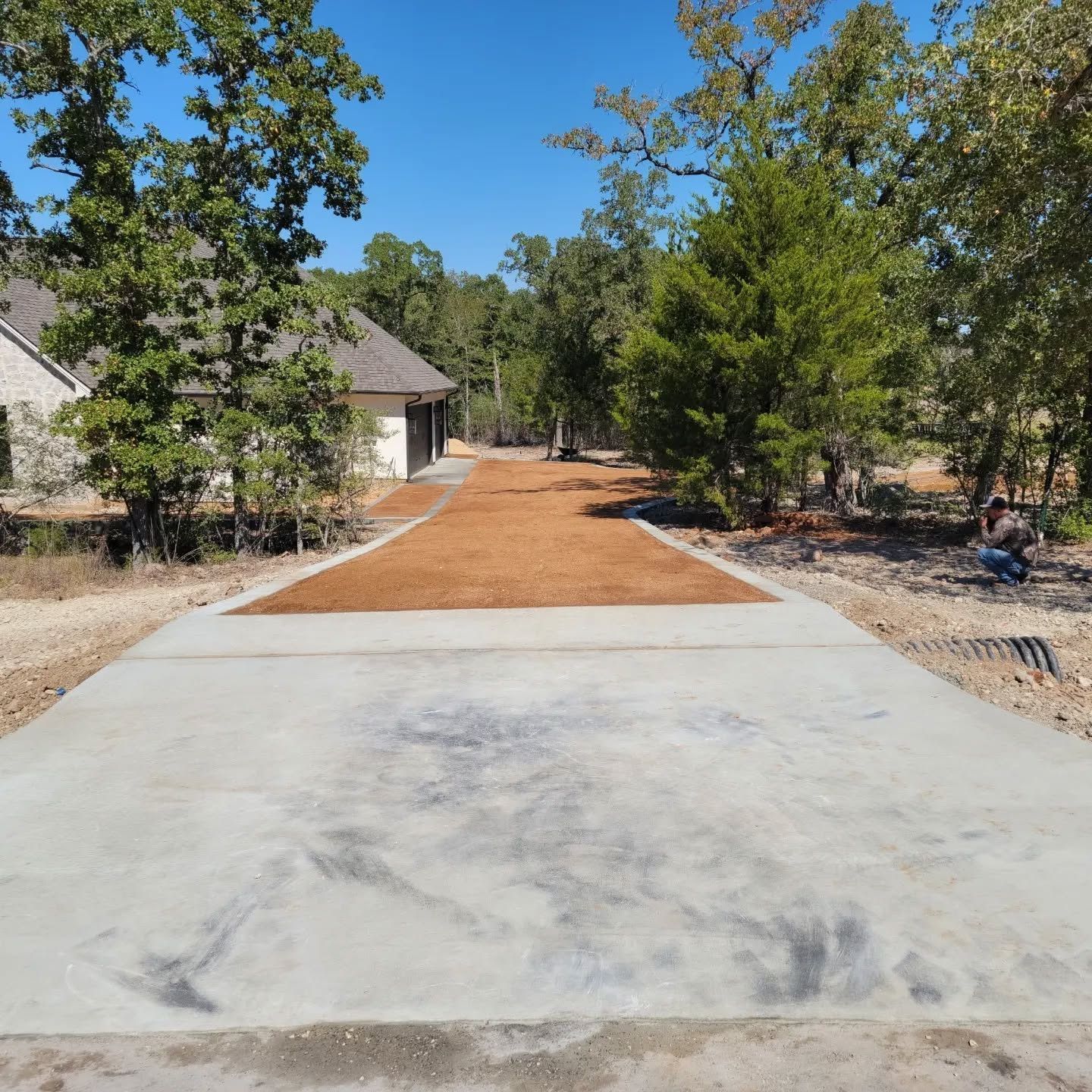 A concrete driveway leading to a house surrounded by trees