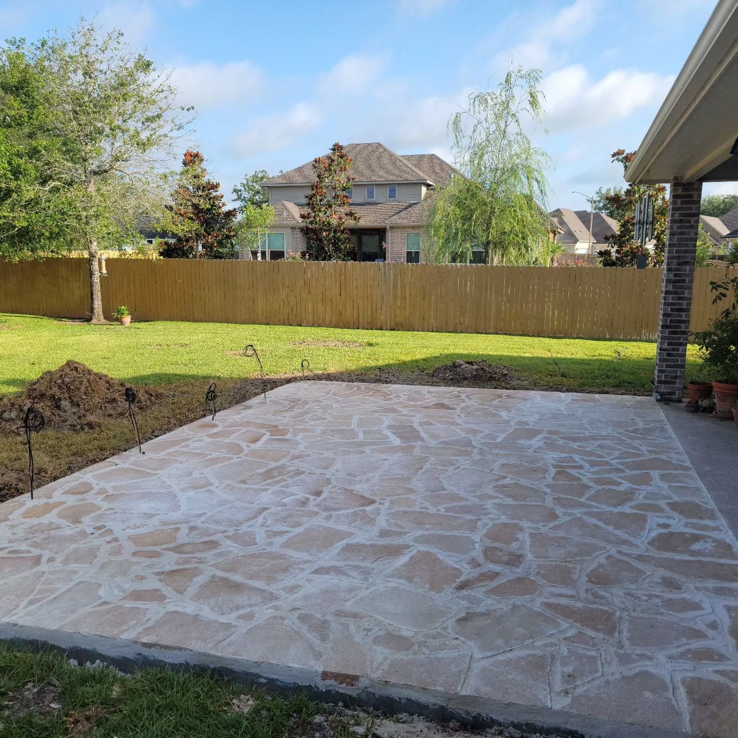 A patio with a wooden fence in the background and a house in the background.