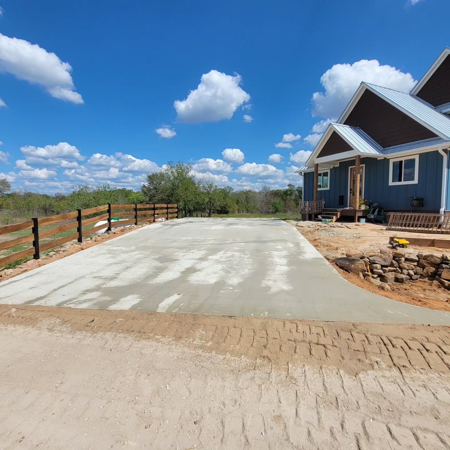 A house with a fence and a concrete driveway in front of it