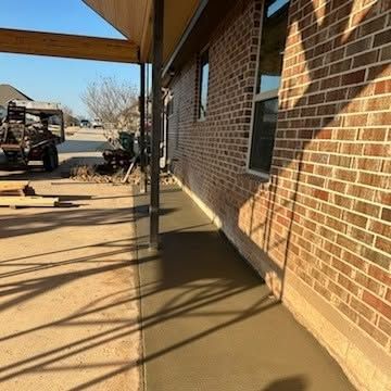 A sidewalk is being built in front of a brick house.