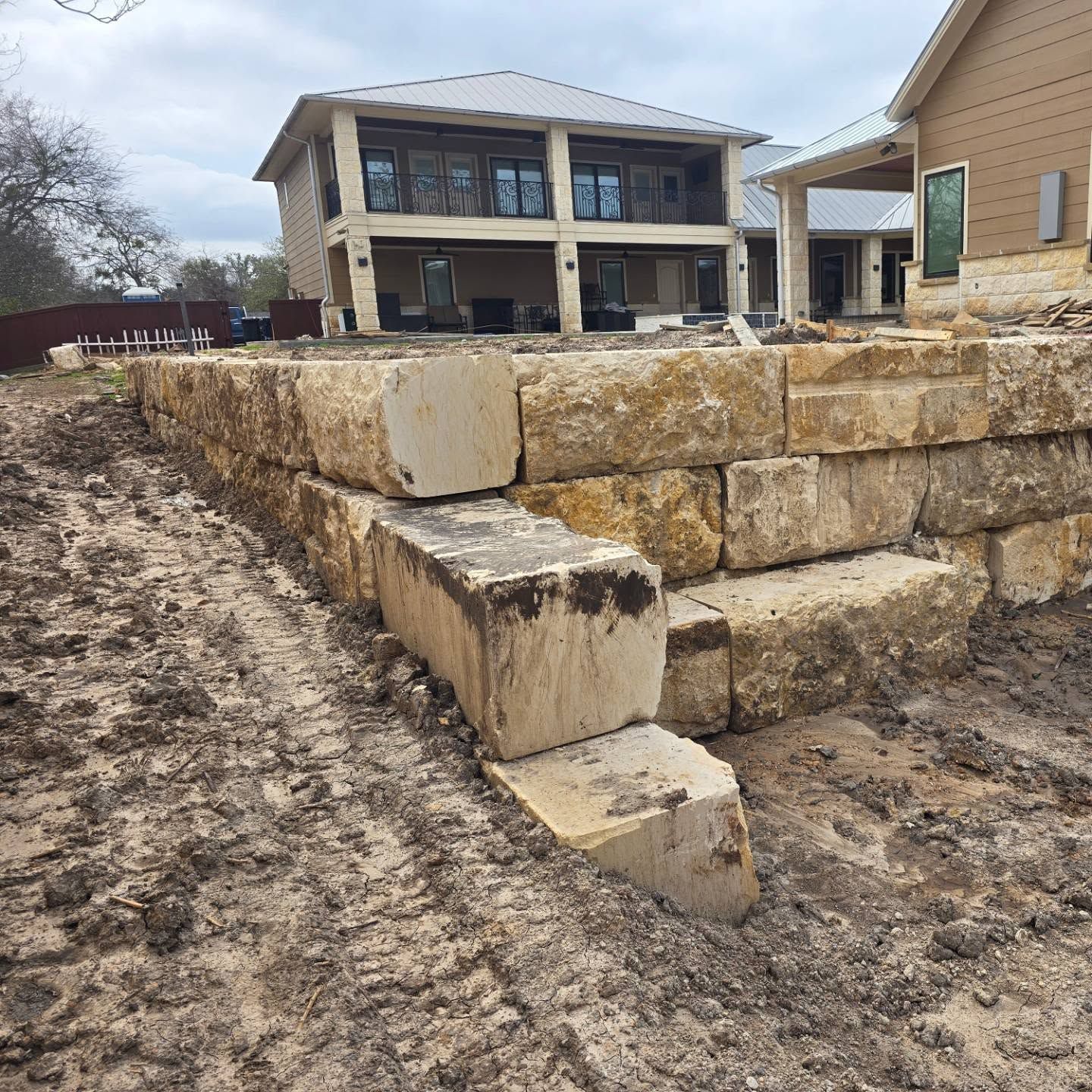 A large stone wall is being built in front of a house.