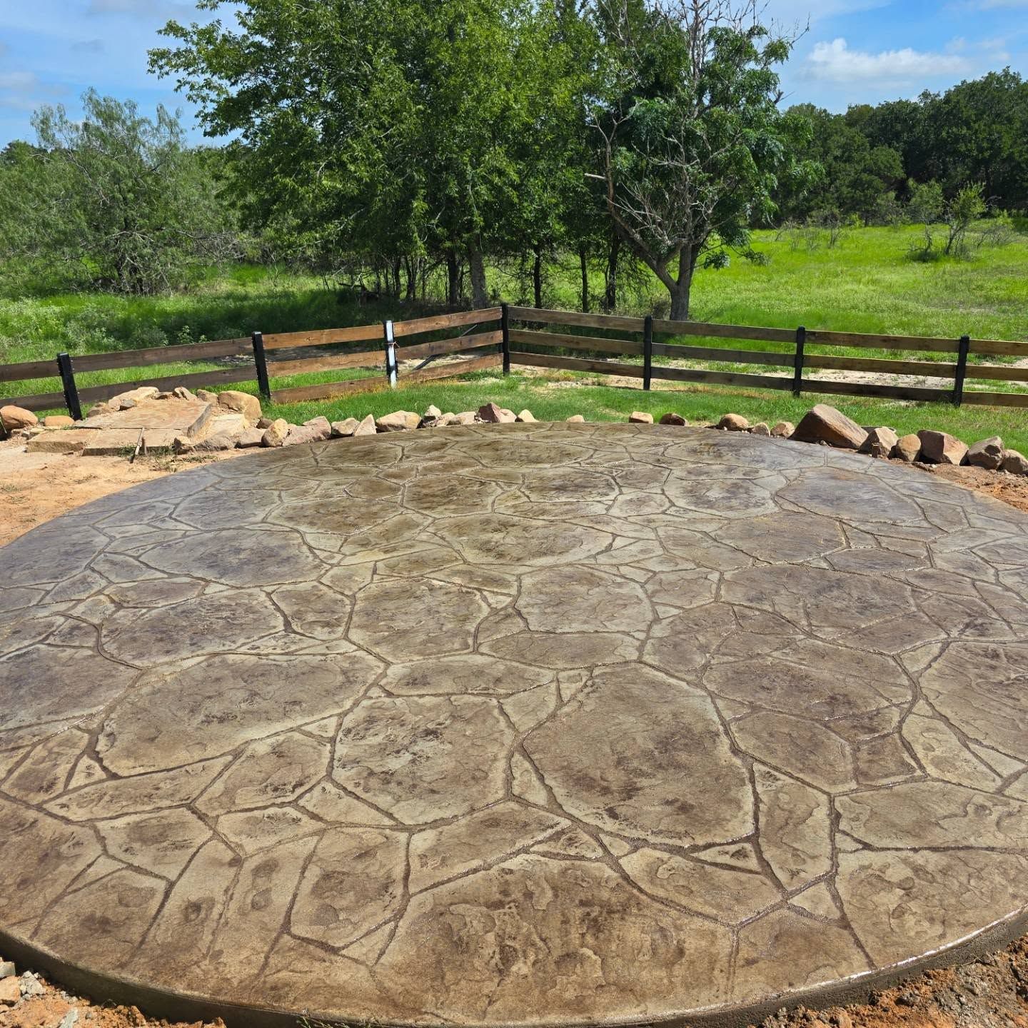 A circular concrete patio with a wooden fence in the background