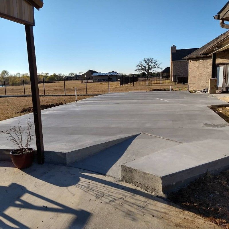 A concrete driveway with a brick house in the background