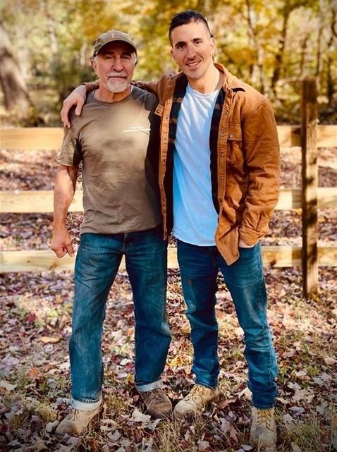 Two men pose together outdoors.