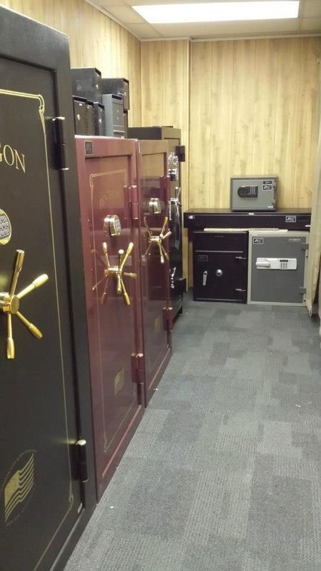 Several safes of different sizes and colors in a room with wood paneling and carpet.