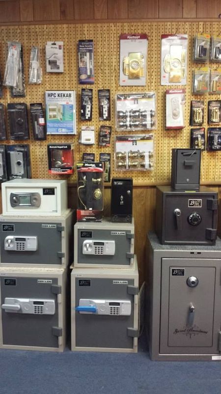 Safes of various sizes, with related hardware on pegboard background, displayed in a store setting.