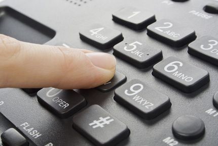 Finger pressing a black telephone keypad close-up