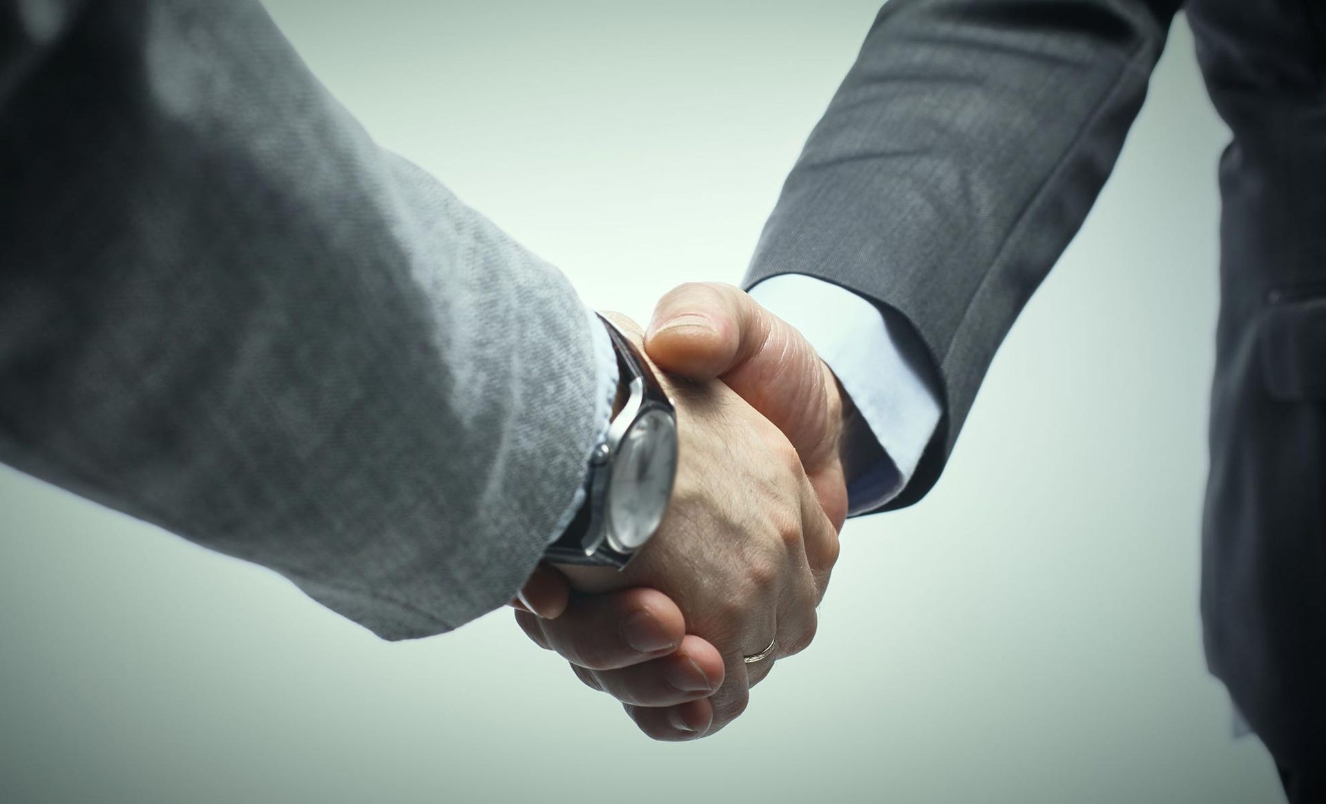 Two men in suits shaking hands, symbolizing a deal.