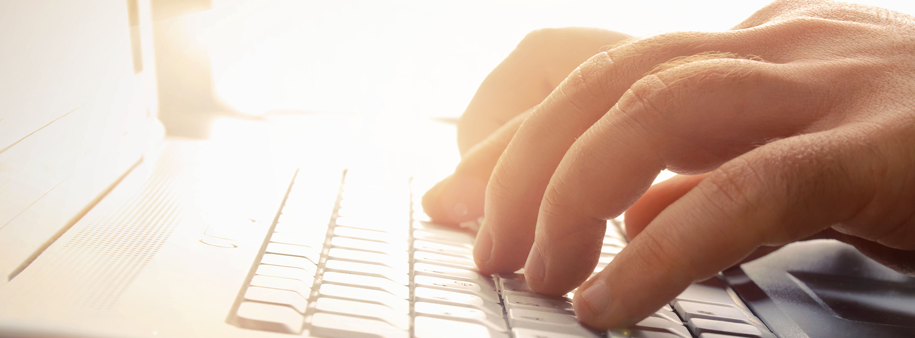 Person typing on a laptop keyboard. Close-up of hands and keys.