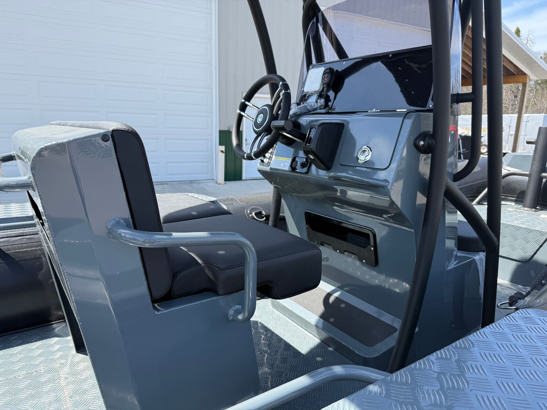 Boat interior with steering wheel, seat, and dashboard in gray.