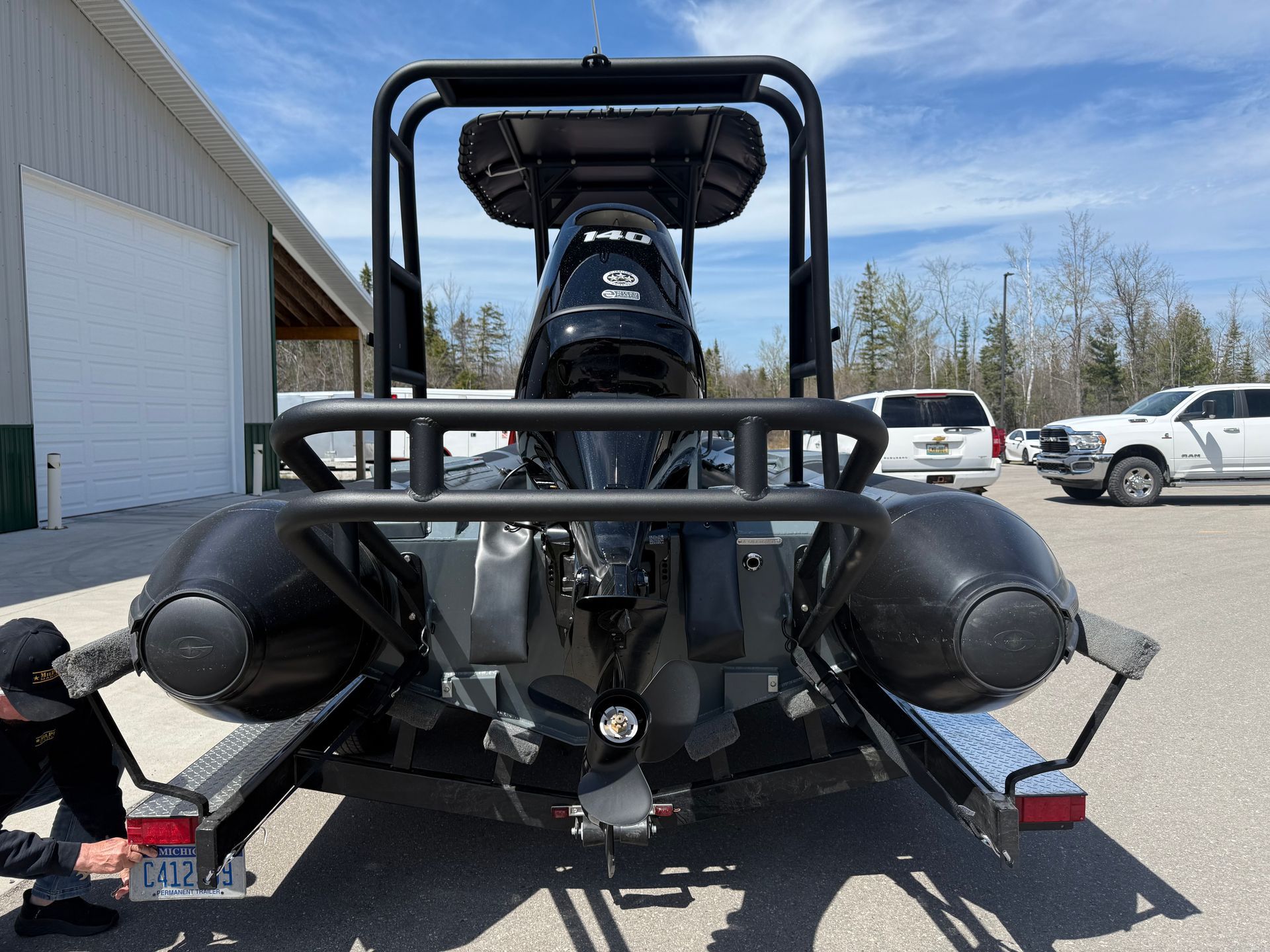 Rear view of a black rigid inflatable boat with an outboard motor, parked on a trailer.