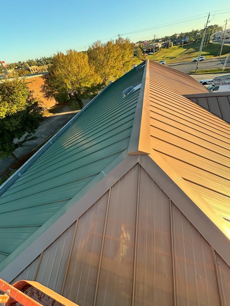 Green and gold metal roof with ridgeline in the sunlight.