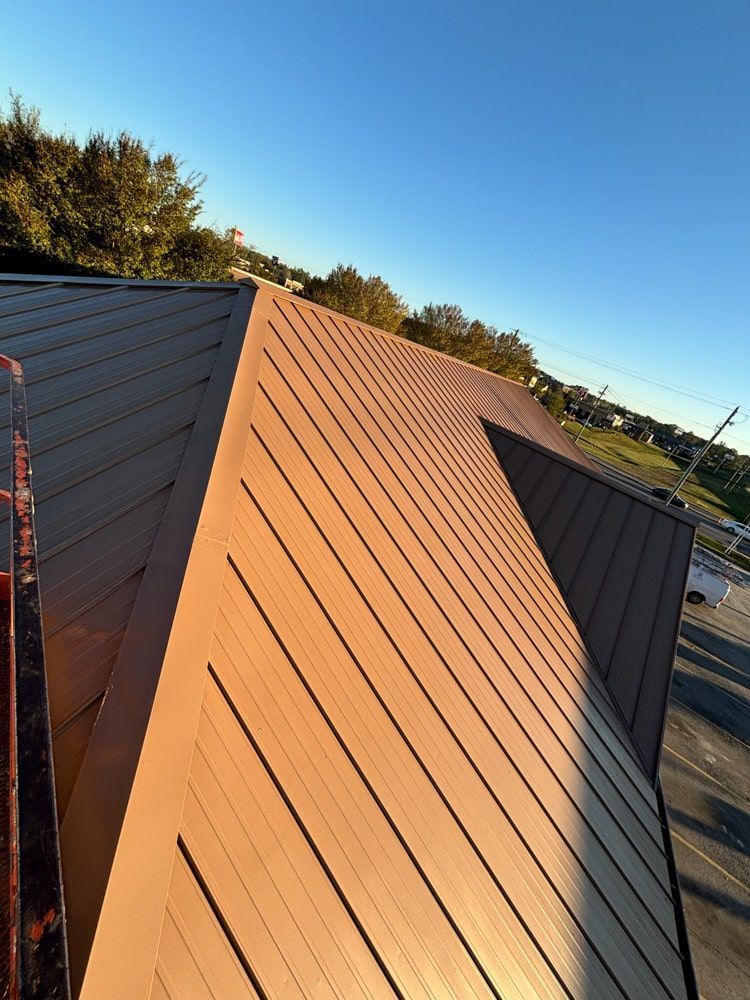 Brown metal roof angled against a blue sky.