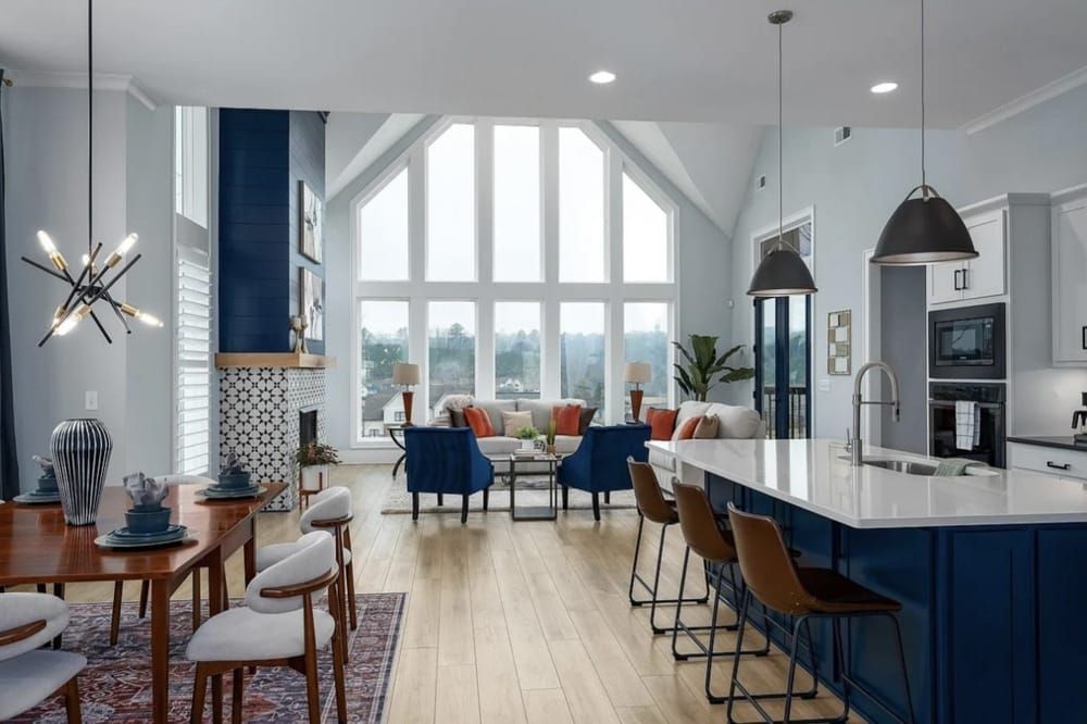 Spacious living area with kitchen island, dining table, and large windows overlooking a scenic view.