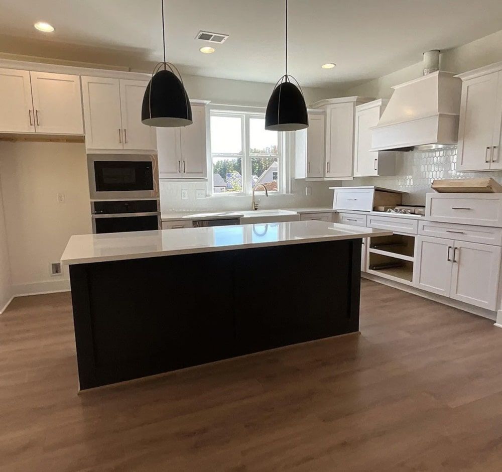 Modern kitchen with white cabinets, black island, and pendant lights.