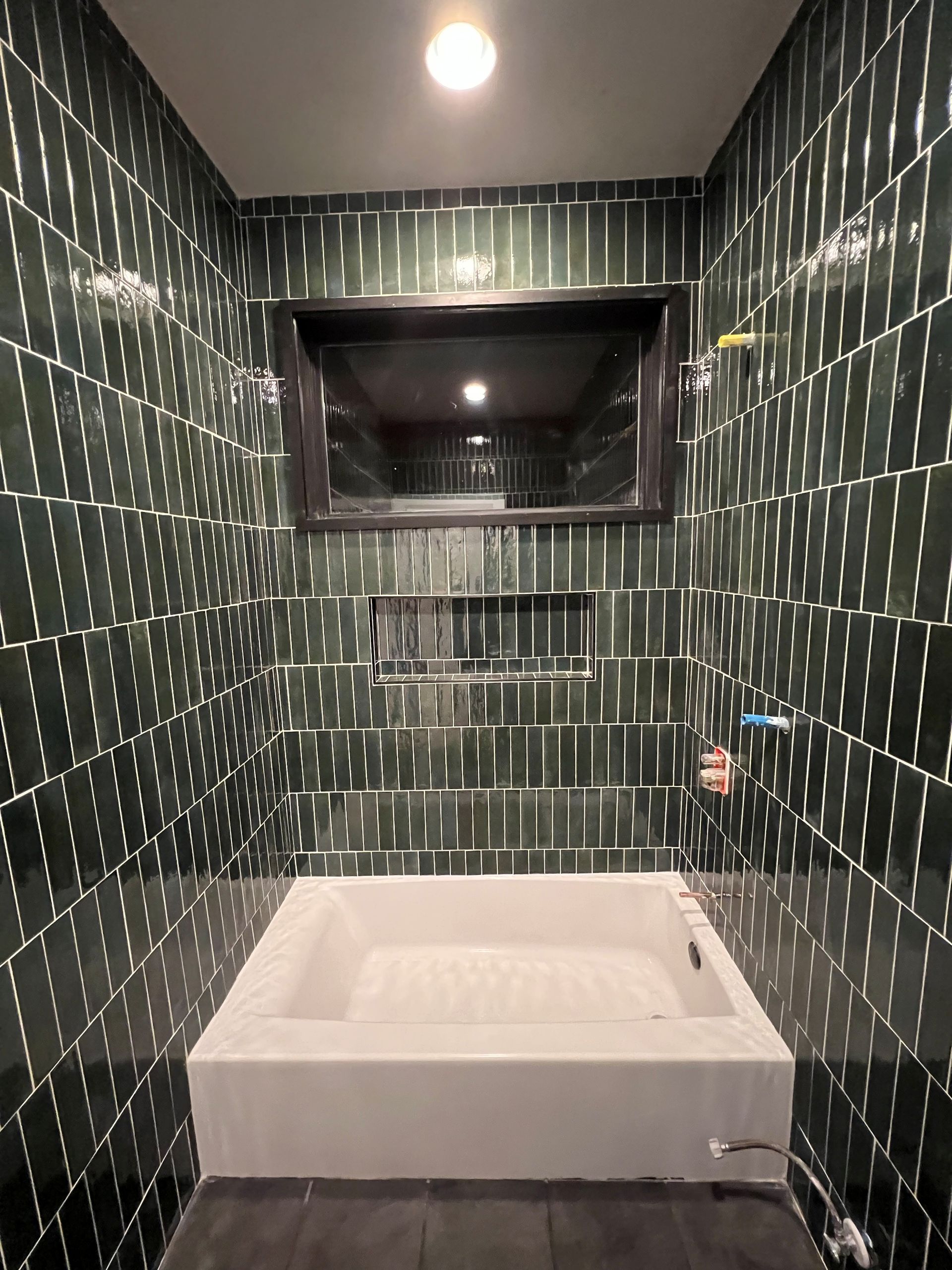 Green tiled bathroom with a white rectangular sink and a mirror.