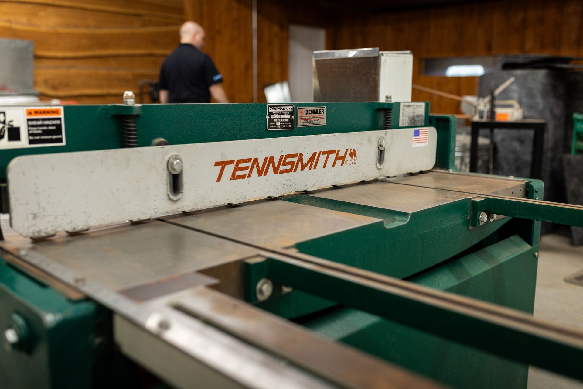 Green Tennsmith metal shear in a workshop; a person is in the background.