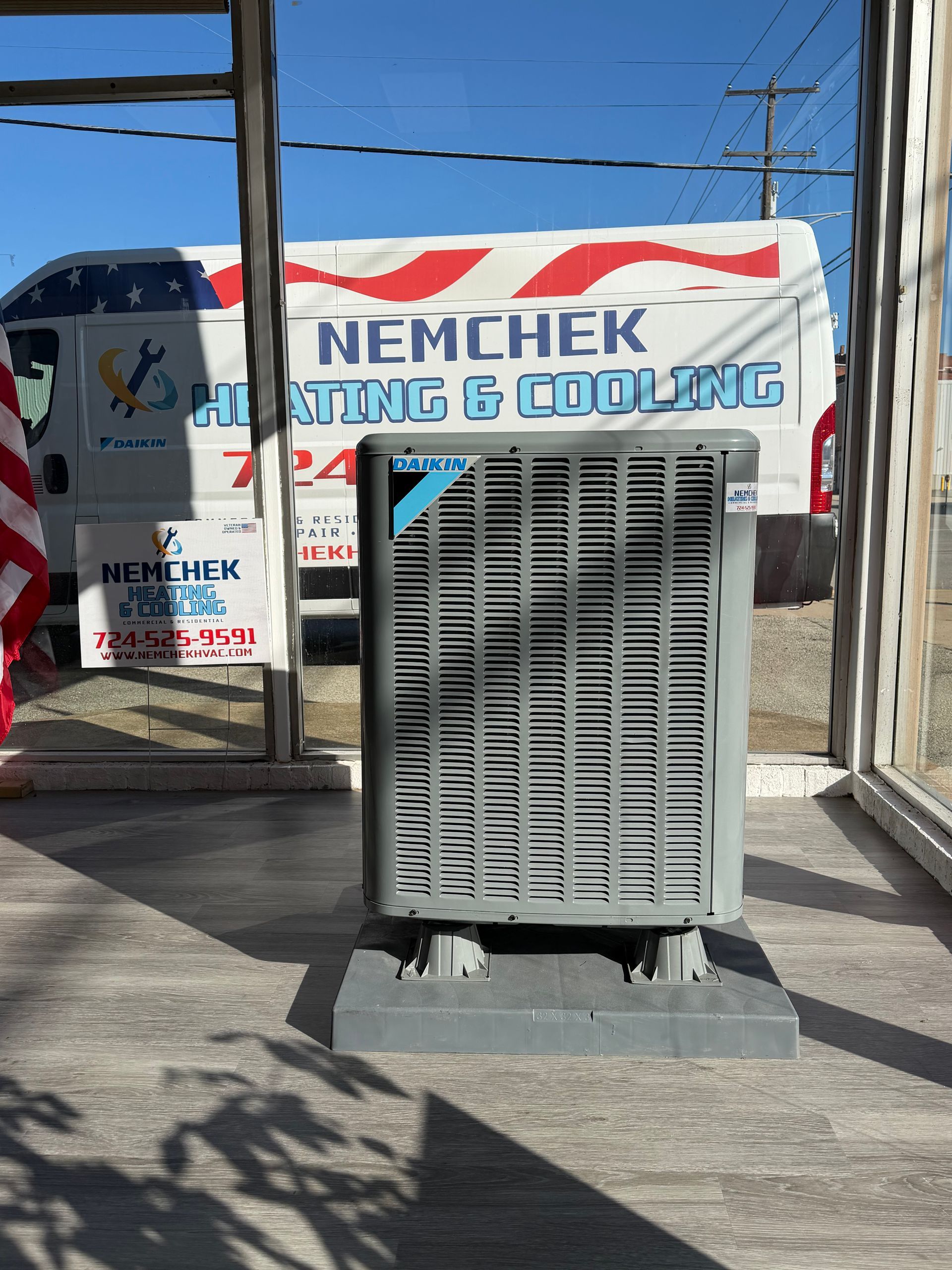 Large gray air cooler in front of a Menchem Cooling sign and truck under a clear blue sky