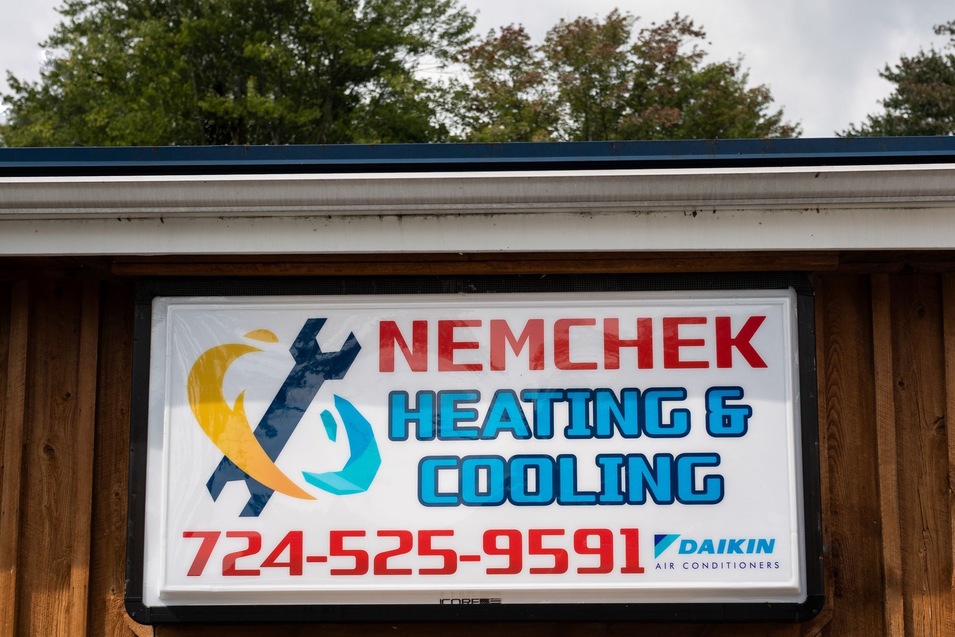 Nemchek Heating & Cooling sign with blue, red, and yellow branding and phone number 724-525-9591
