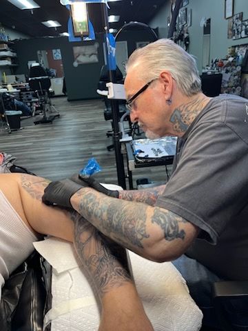 A woman is getting a tattoo on another woman 's back