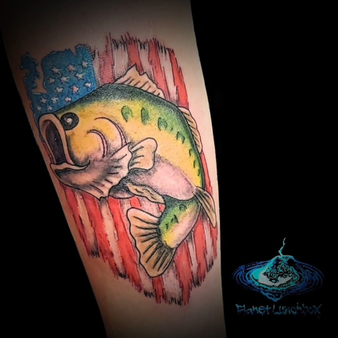 Colorful fish tattoo over an American flag background on a forearm