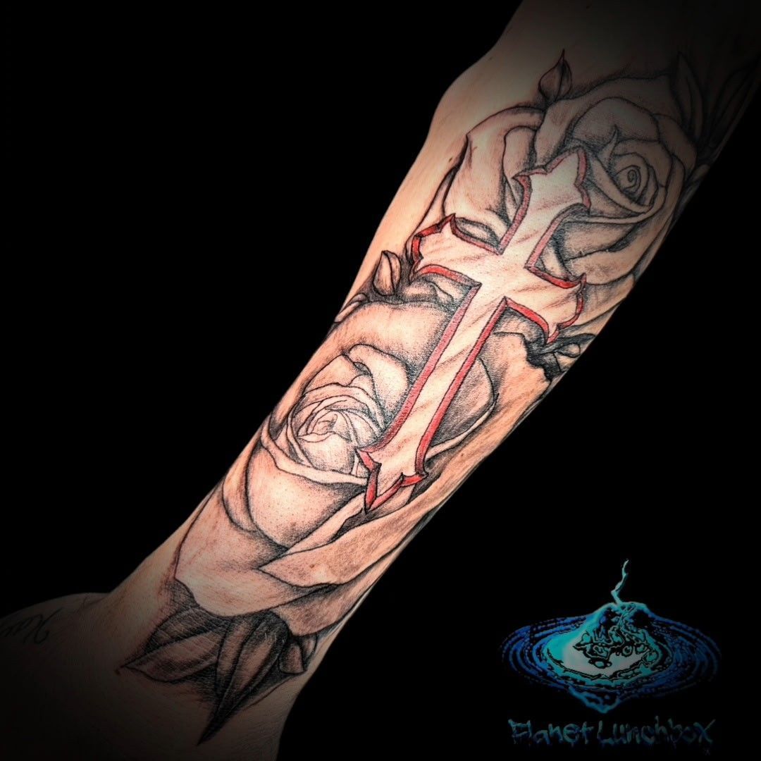 Tattooed forearm with a black-and-gray illustrated face and red accents on a black background