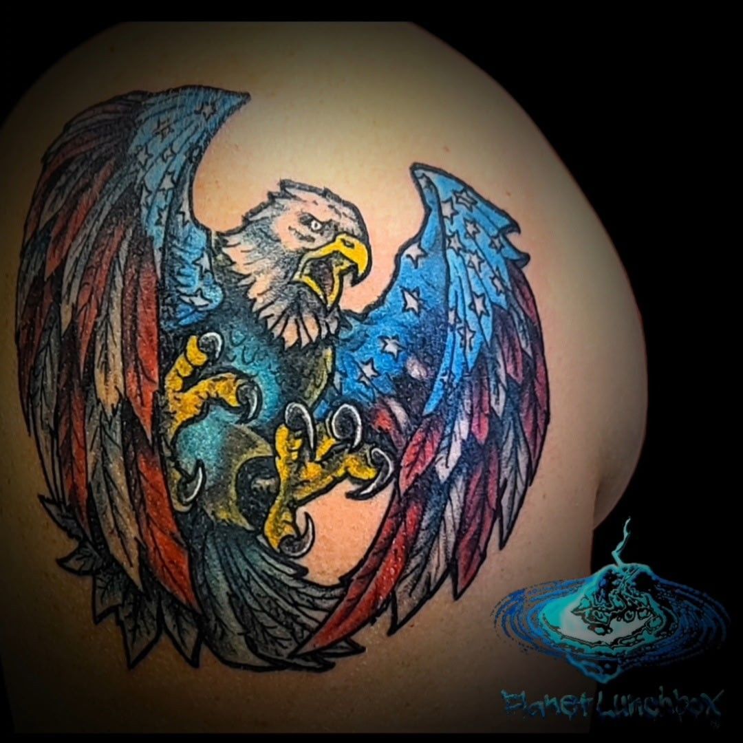 Eagle tattoo with outstretched wings in blue, red, and yellow on skin