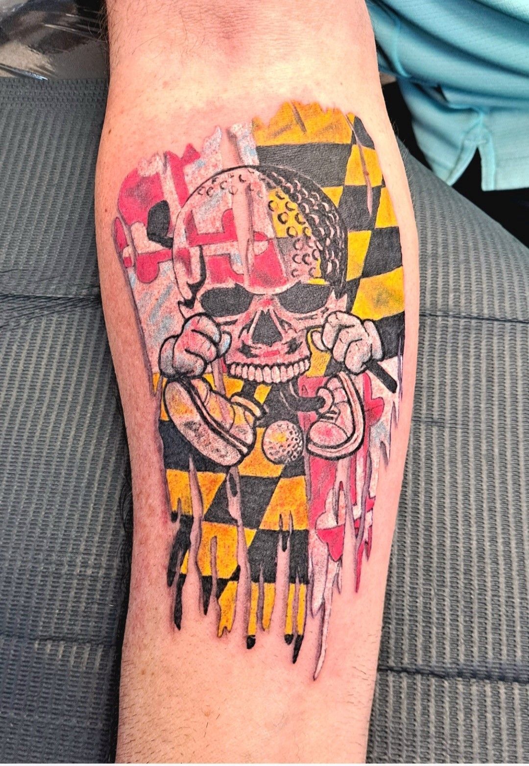 A person has a tattoo of a skull with a flag on their leg.