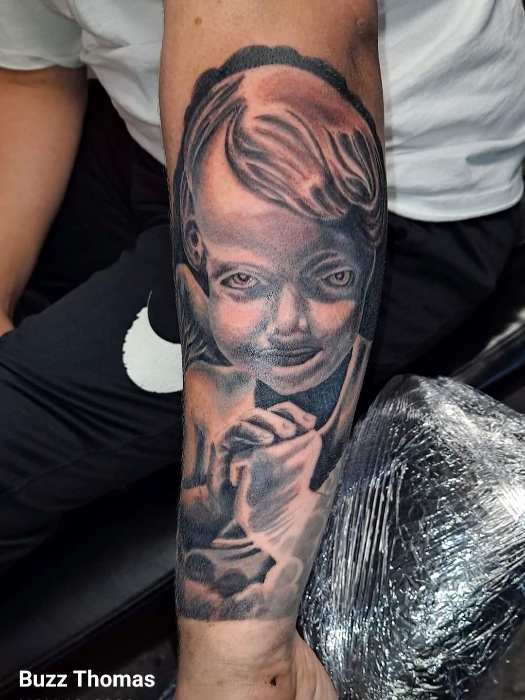 A man has a tattoo of a baby on his arm