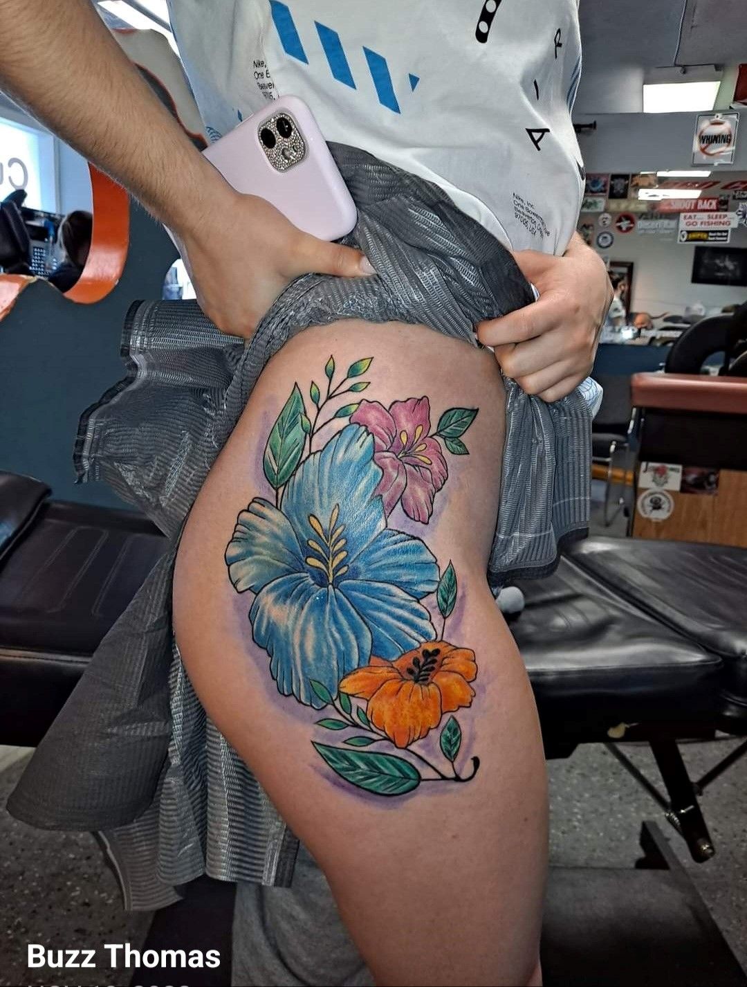 A woman has a tattoo of hibiscus flowers on her hip