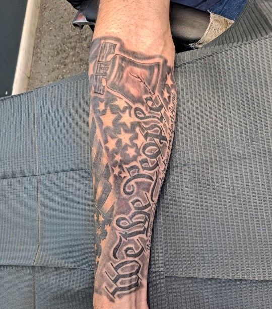 A man has a tattoo on his arm that says we the people
