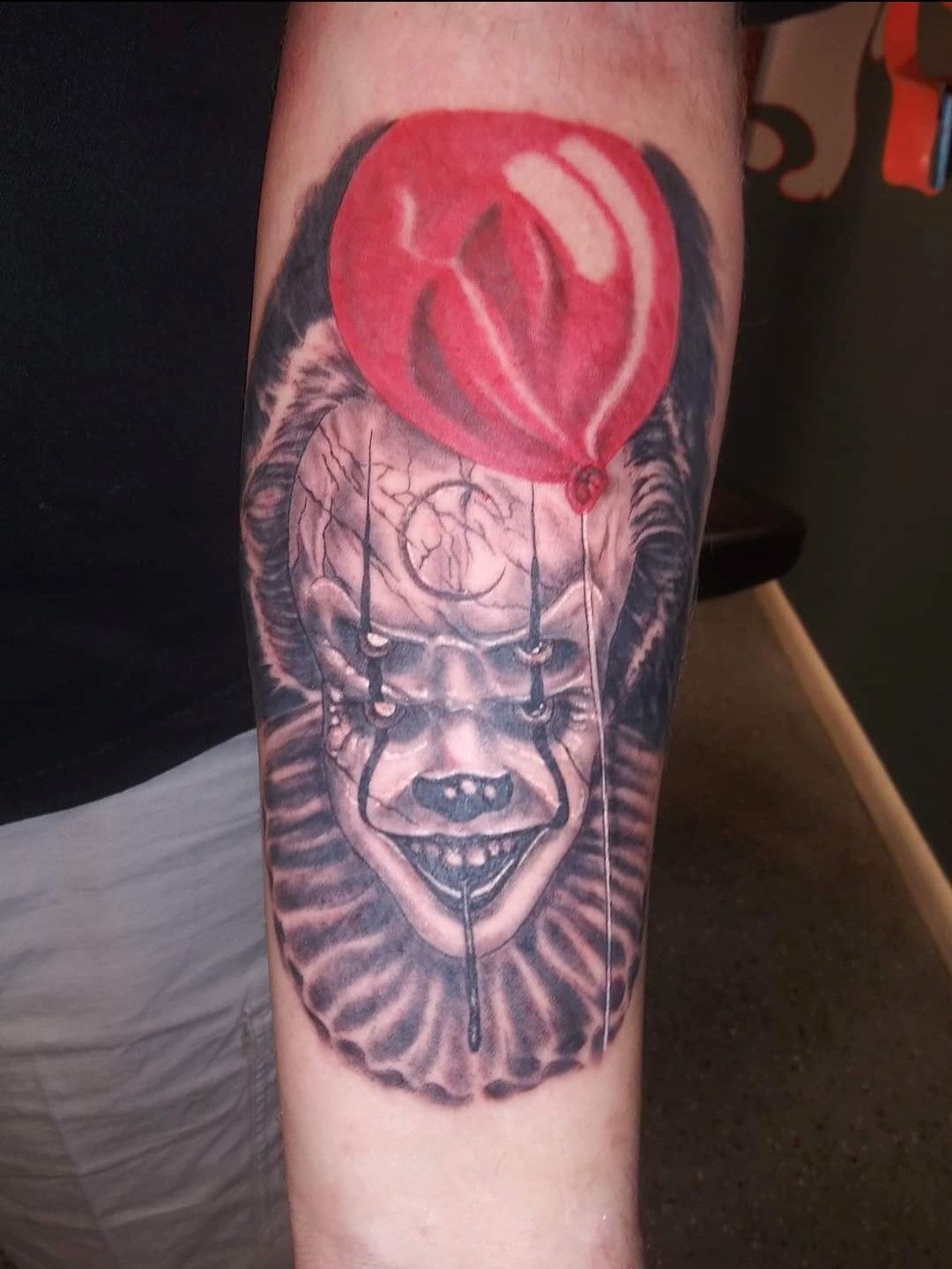 A tattoo of a clown with a red balloon on his head