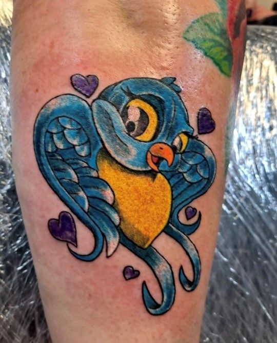 A person has a tattoo of a blue bird on their leg