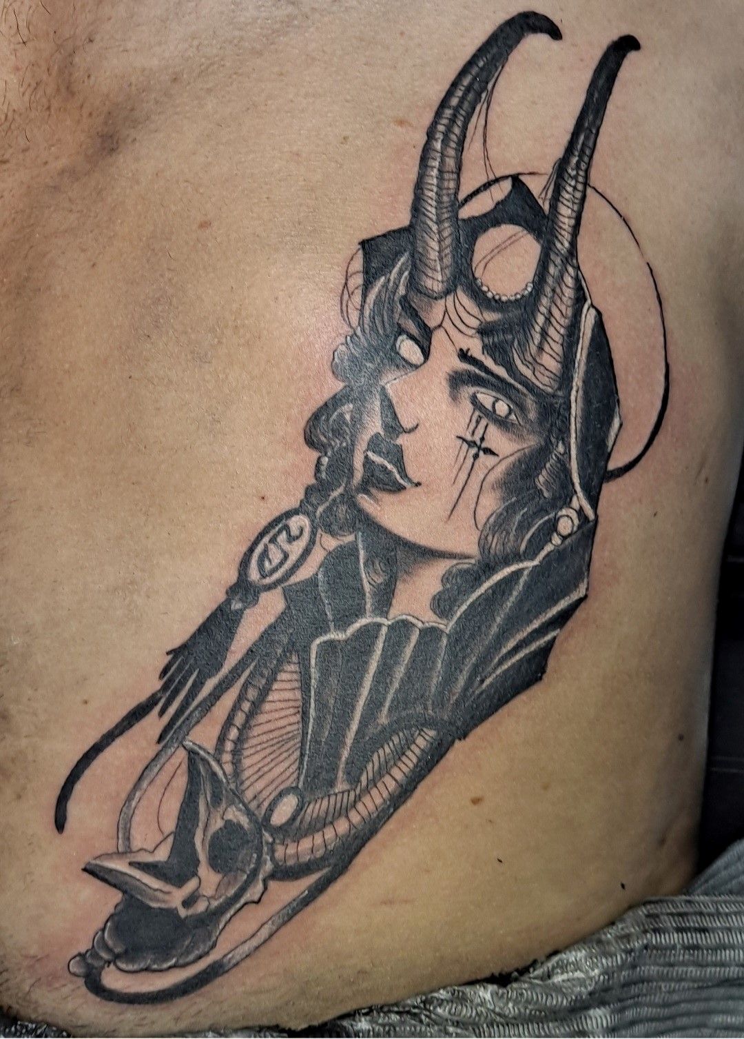 A black and white tattoo of a woman with horns